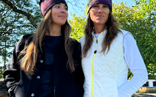 two women wearing 4T2D Fall beanie hats and outerwear standing outside amongst treesside